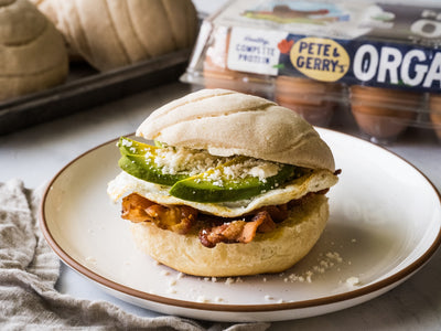 A loaded breakfast sandwich assembled on sweet Mexican concha bread with a fried egg, bacon, avocado, and cotija cheese. | peteandgerrys.com