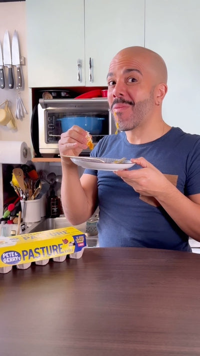 A man eating while sitting by a carton of Pete & Gerry's eggs 
